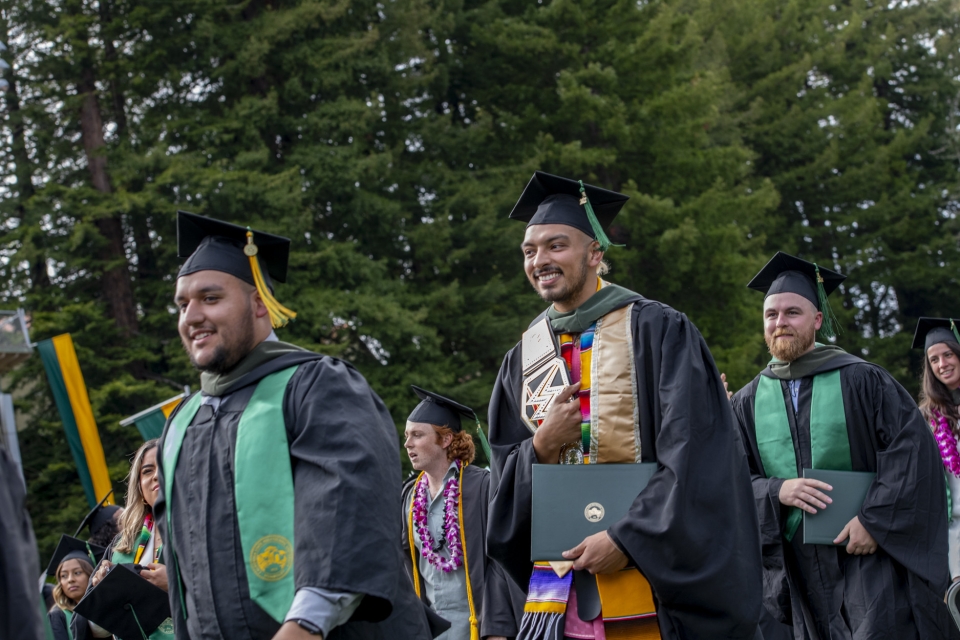 graduate students walking with their diploma covers at commecement 