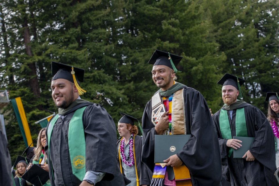 graduate students walking with their diploma covers at commecement