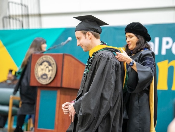 a graduate student getting hooded at fall 2022 graduation by the dean of graduate studies. 